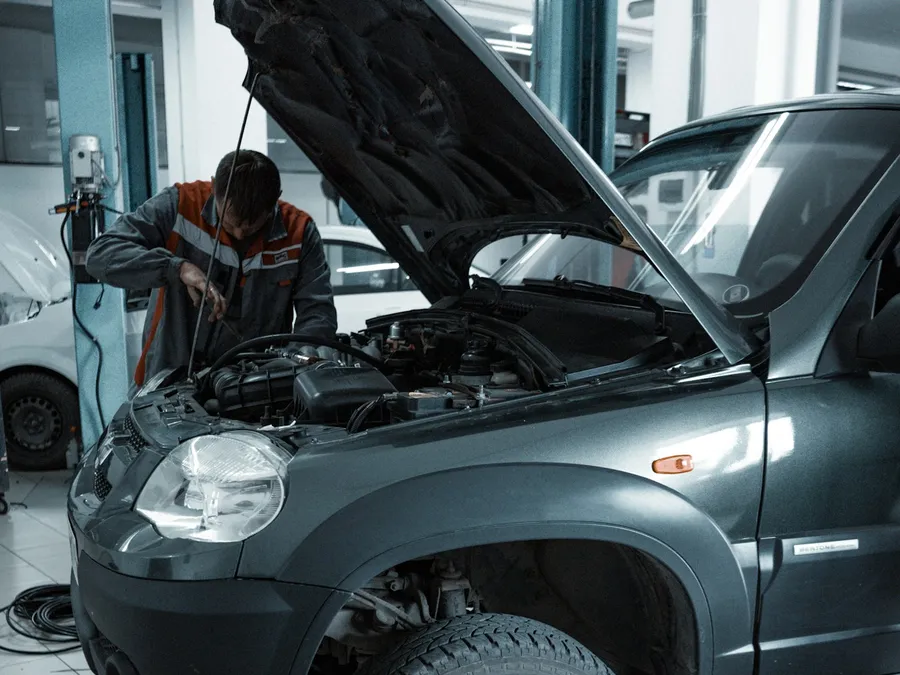 A mechanic works under the hood in a repair shop